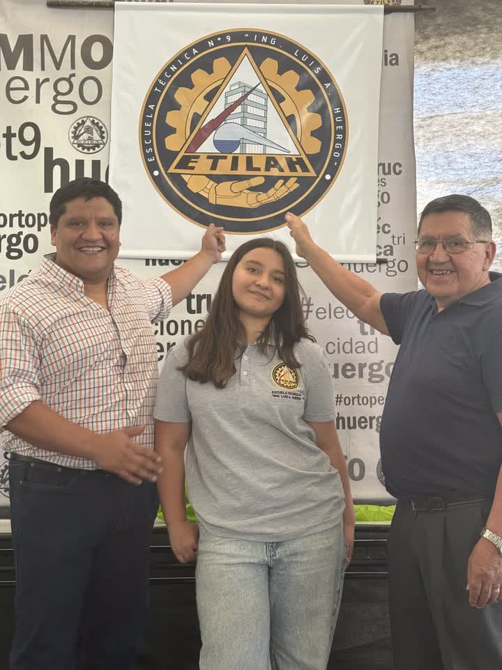 Marcelo junto a su papá y su hija frente al nuevo logo de la Escuela Técnica Huergo, que incorpora una mano protésica al diseño.